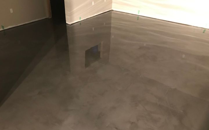 Glossy gray coated floor in a basement room with white walls