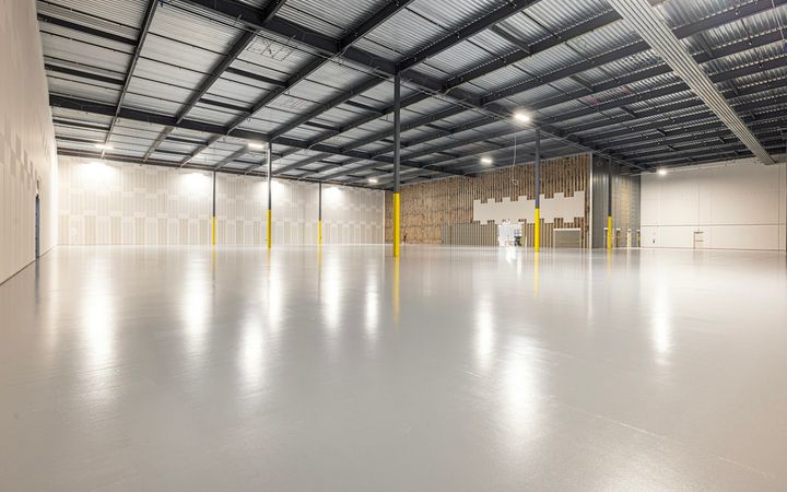 Empty warehouse with a glossy polished concrete floor under rows of lights
