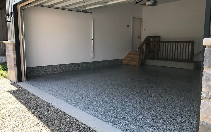 Open garage door with daylight falling on a speckled gray floor